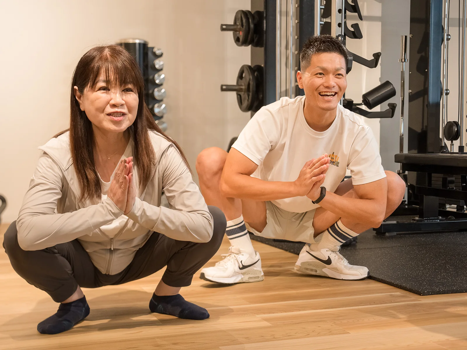 Happilyでトレーナーと笑顔でスクワットをする40代・50代女性